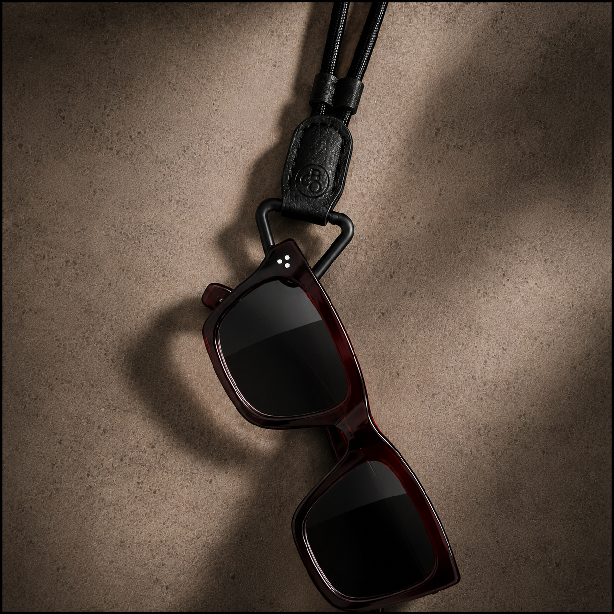Thicker acetate sunglasses placed through The Signature's matte-black loop