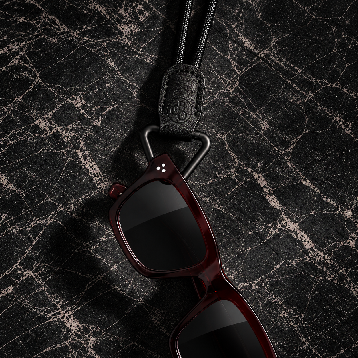 Close view of sunglasses carried through The Signature Eyewear Necklace loop and leather holder